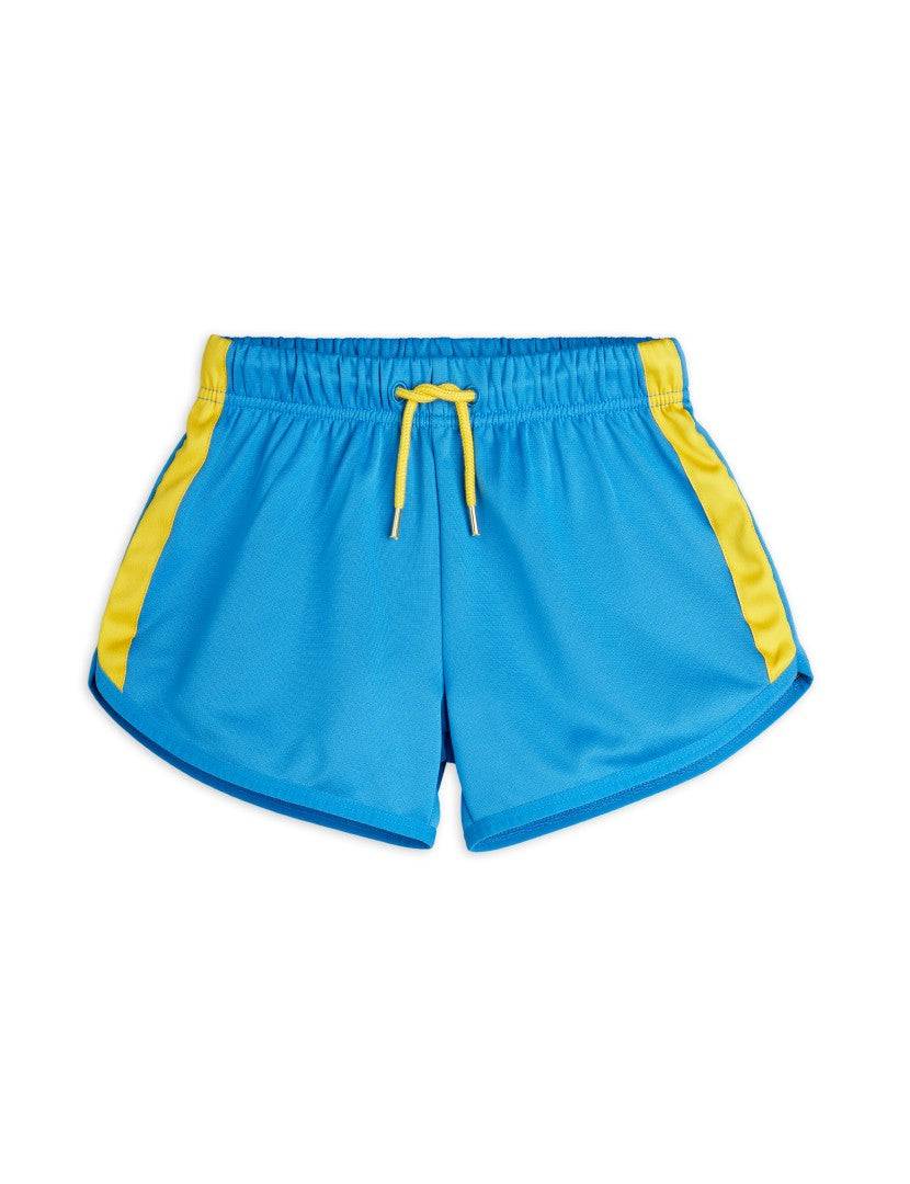 WCT Shorts in Blau mit gelben Seitenstreifen und elastischem Bund, ideal für Kinder von 2 bis 12 Jahren. Perfekt für sportliche Aktivitäten im Sommer.