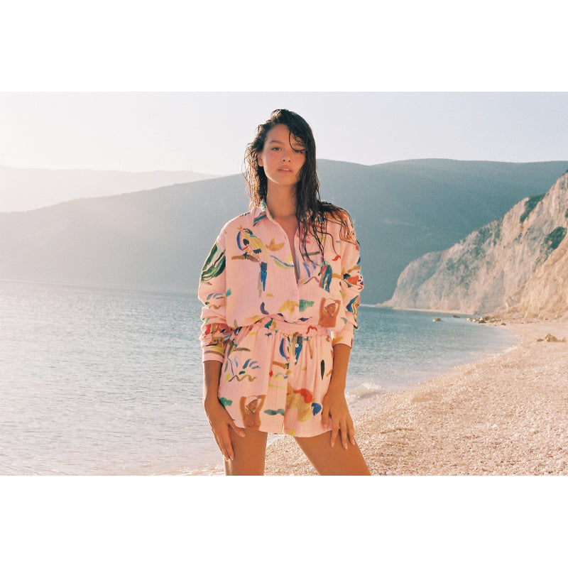 Model trägt Abra Rossa Cotton Gauze Shorts am Strand, kombiniert mit passendem Hemd für einen luftigen Sommer-Loungewear-Look.