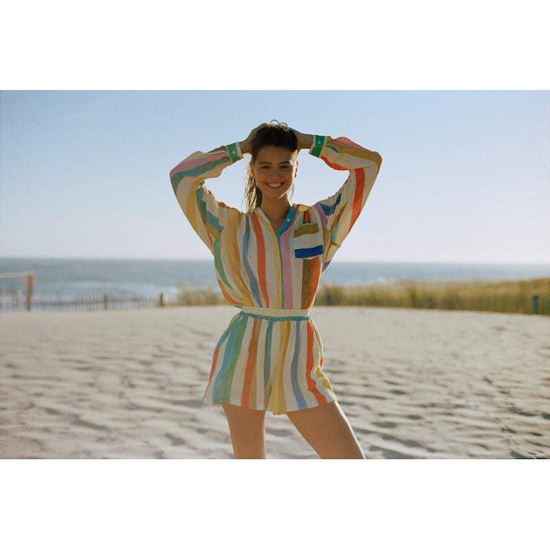 Frau trägt Paz Cotton Gauze Shorts aus 100% Baumwolle mit elastischem Bund am Strand, kombiniert mit passendem Hemd für sommerlichen Look.
