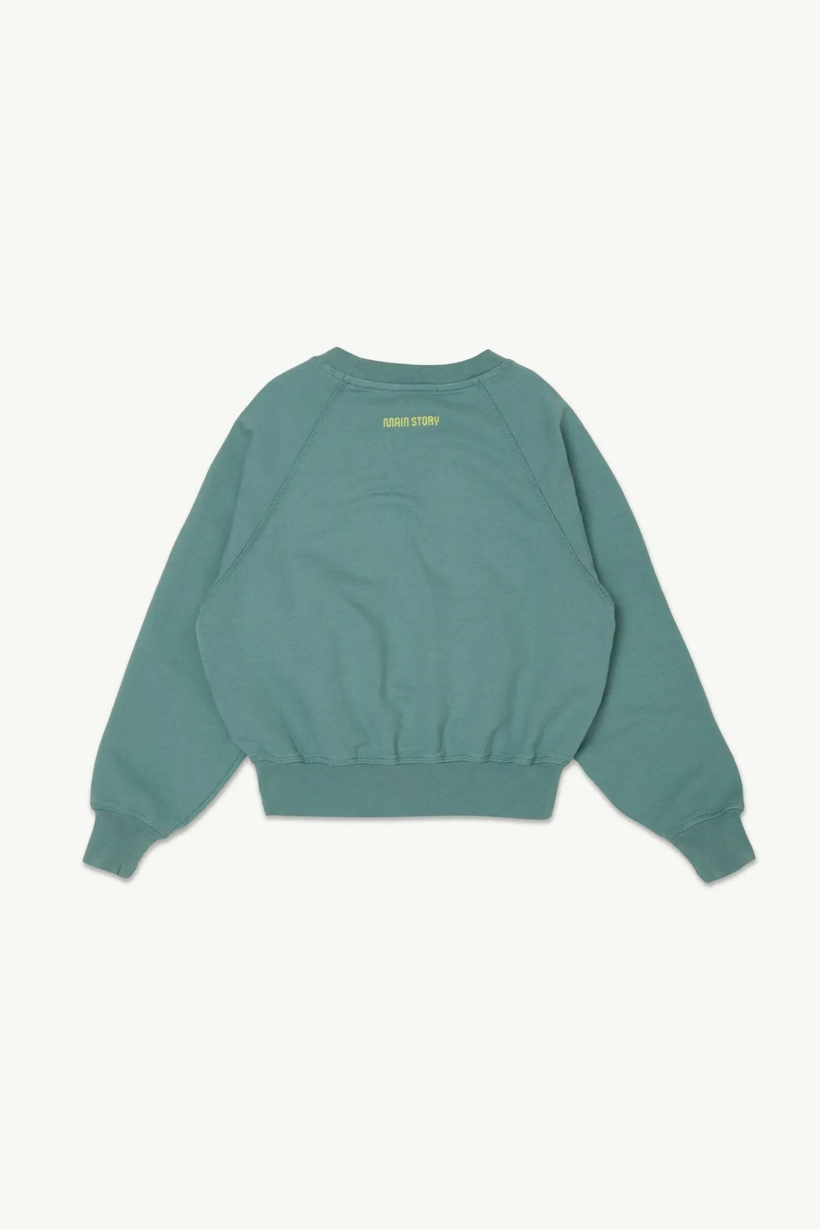 Rückansicht des Raglan Sweat Smoke Blue Fleece Pullovers mit gelbem Main Story Schriftzug im Nackenbereich, ideal für Kinder von 4 bis 10 Jahren.
