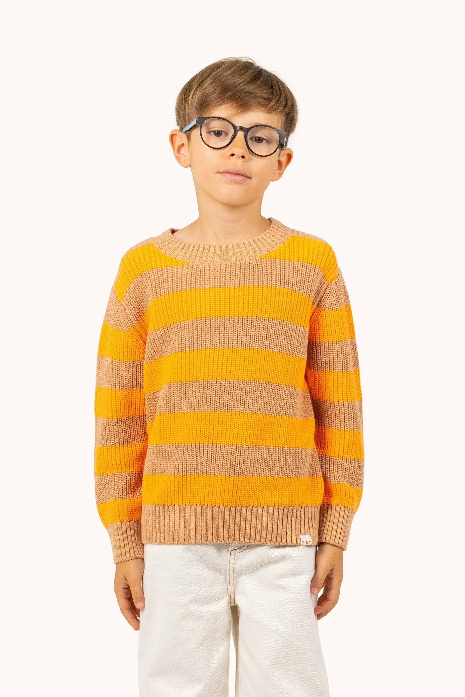 Kind trägt Stripes Knit Sweater yellow/ pastel pink mit auffälligem Streifenmuster, perfekt für Jungen und Mädchen im Alter von 2 bis 9 Jahren.