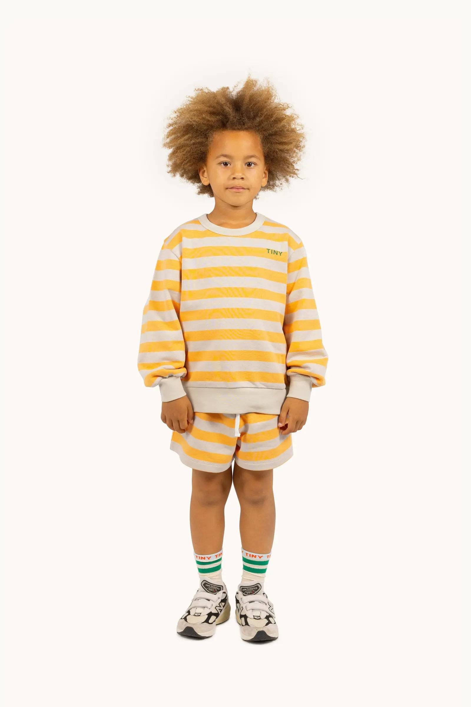 Kind trägt Stripes Sweatshirt orange/ dark vanilla von Tinycottons, gestreiftes Oberteil für Jungen und Mädchen in Größe 6-7Y aus der SS25 Kollektion.