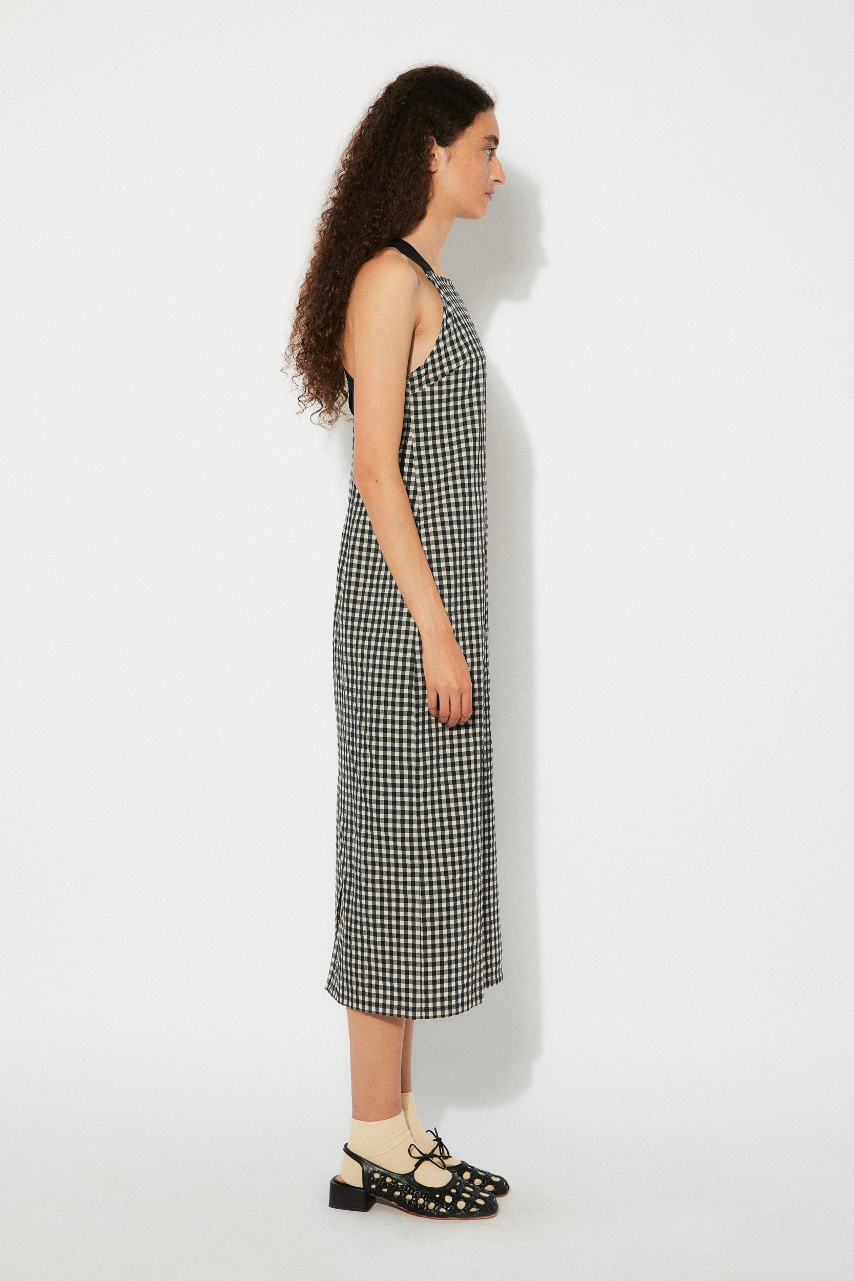 Side profile of the Oyster Dress Black Gingham highlighting its straight-cut silhouette and comfortable fit. A versatile addition to any wardrobe.
