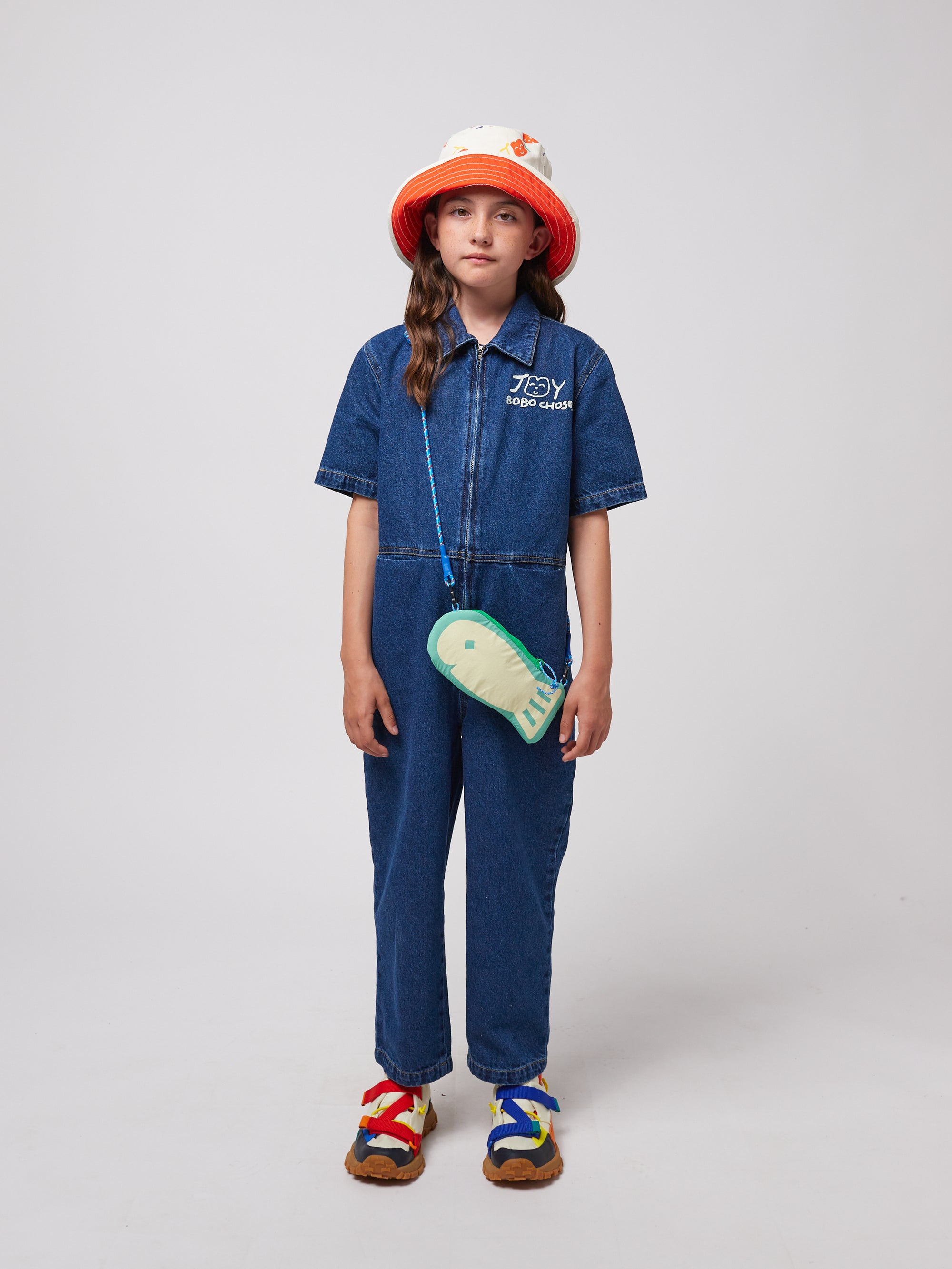 Model wearing the Lucky Fish Hand Bag as a crossbody pouch. The fish-shaped design and blue rope strap add a fun touch to a denim jumpsuit outfit.