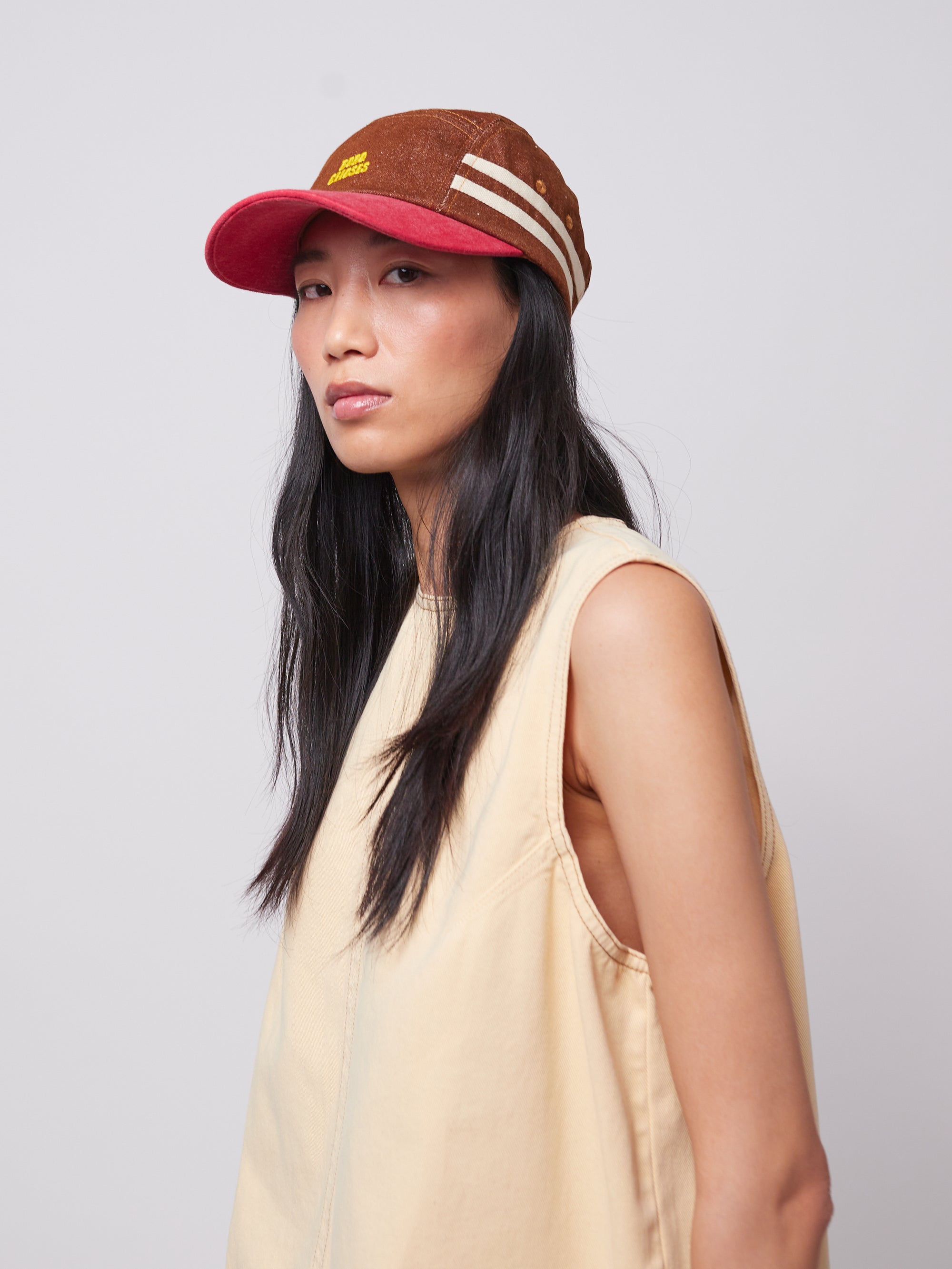 Model wearing Bobo Choses cap with a brown canvas body, red brim, and striped side details. Stylish and durable hat for women’s casual wear.