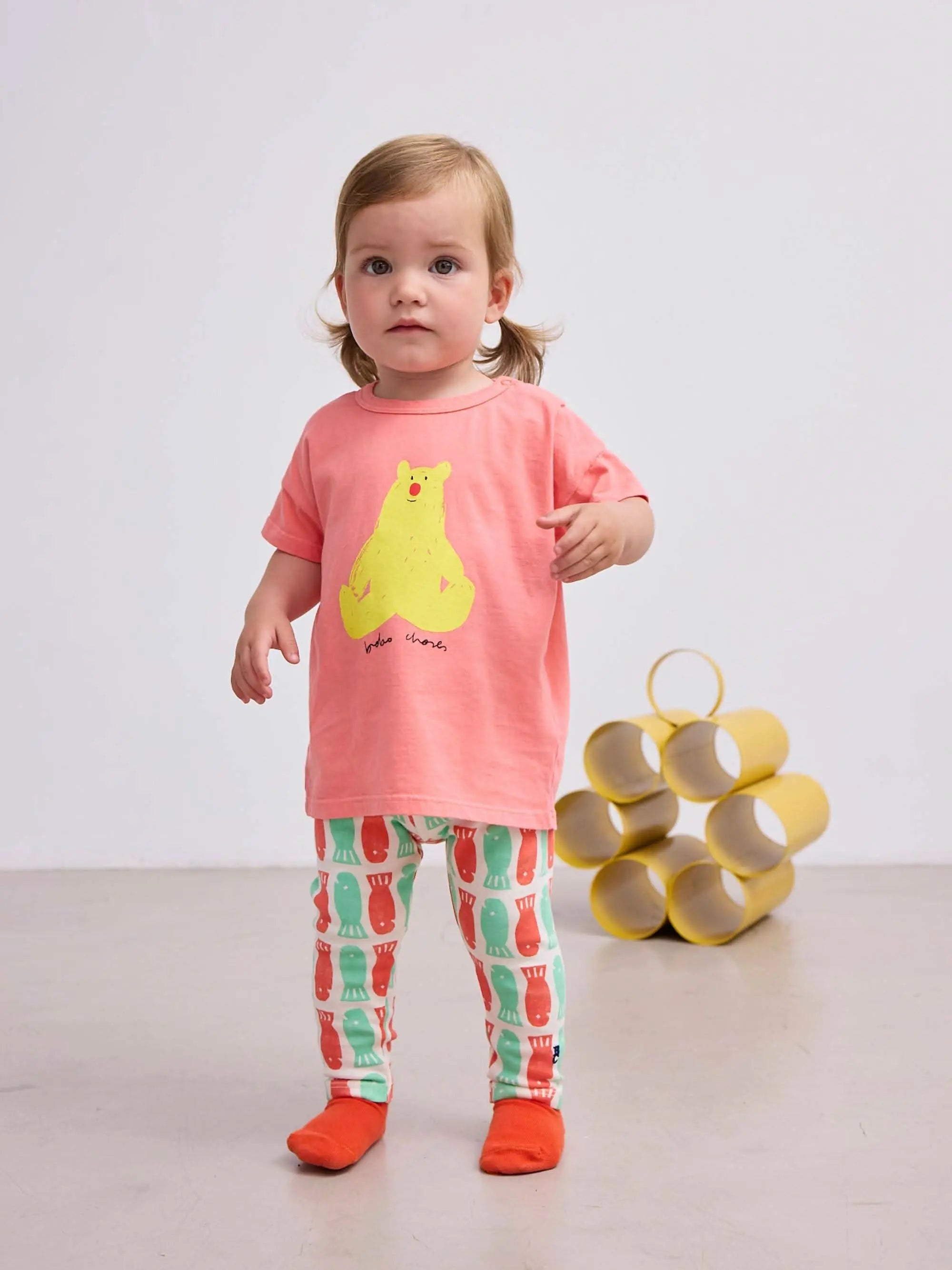 Baby trägt Baby Hug Me Bear T-shirt in Rosa mit gelbem Bärenprint, ideal für 0–24 Monate in der Kategorie Baby Tops.