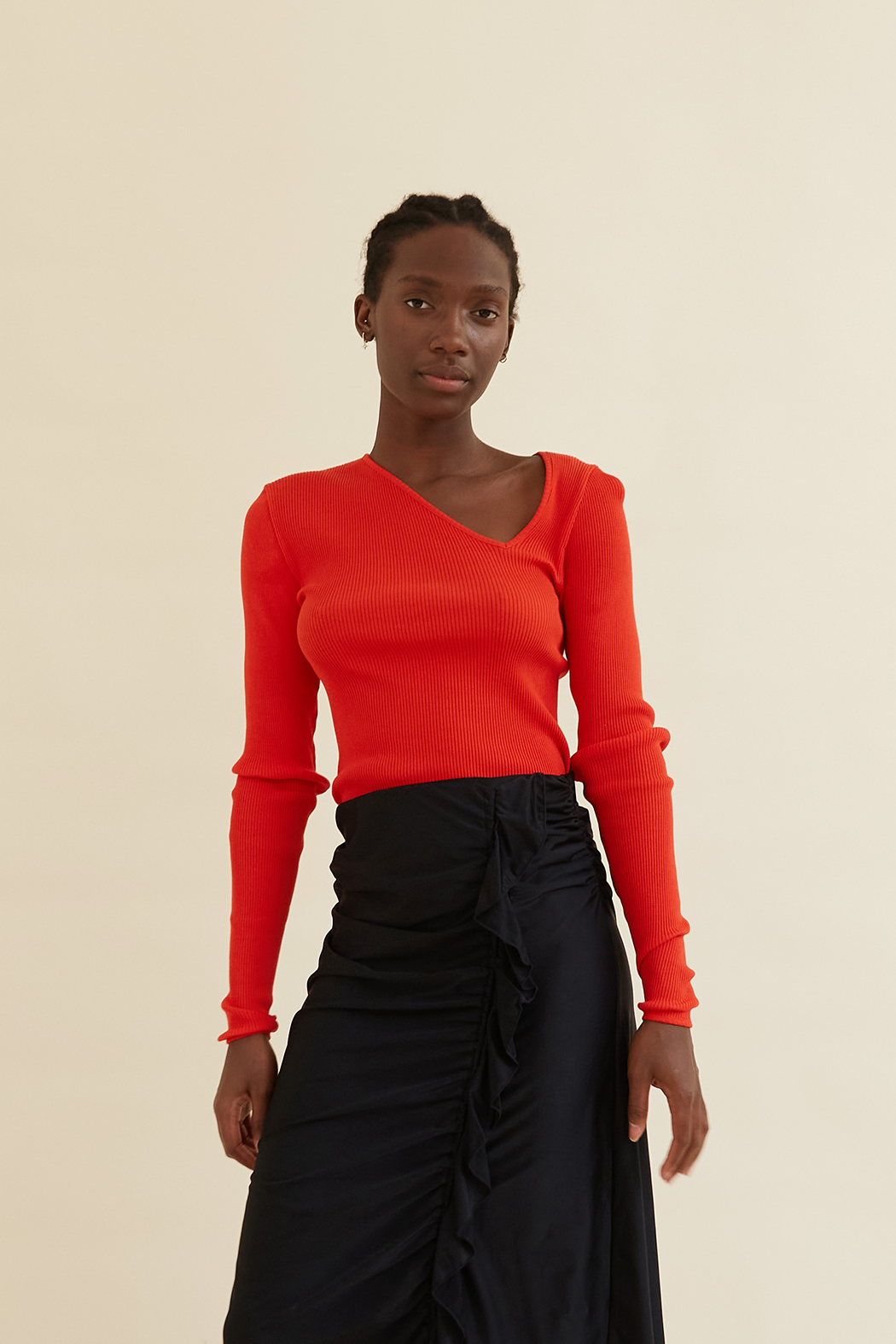 Amèlie Seamless Top in Organic Cotton, featuring a bold red hue, asymmetrical neckline, and ribbed texture. Perfect snug fit with stylish ruffled details.