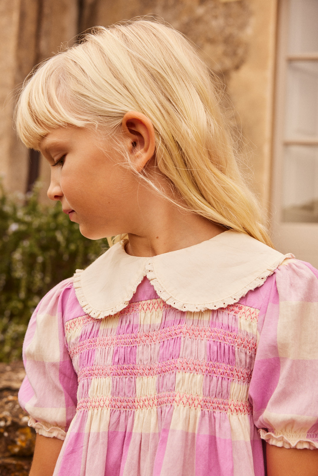 Close-up of the Lalie Smoked Dress Check Lila, showcasing delicate smocking details and a contrasting Peter Pan collar. Made from 100% cotton for a soft feel.